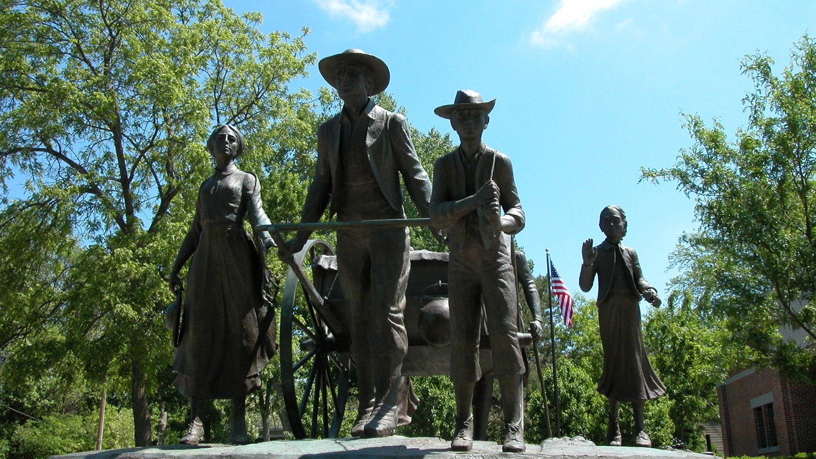 A sculpture of pioneers pulling a handcart, set in a park.