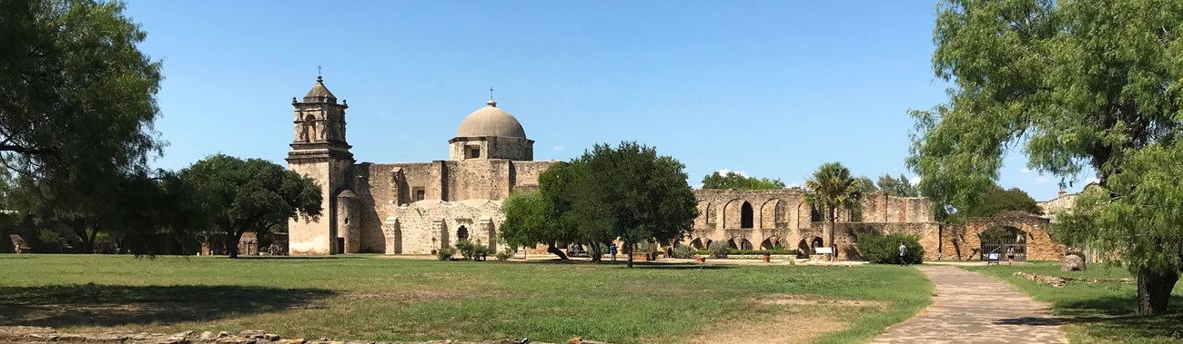 A path leads to a spanish-colonial style mission.