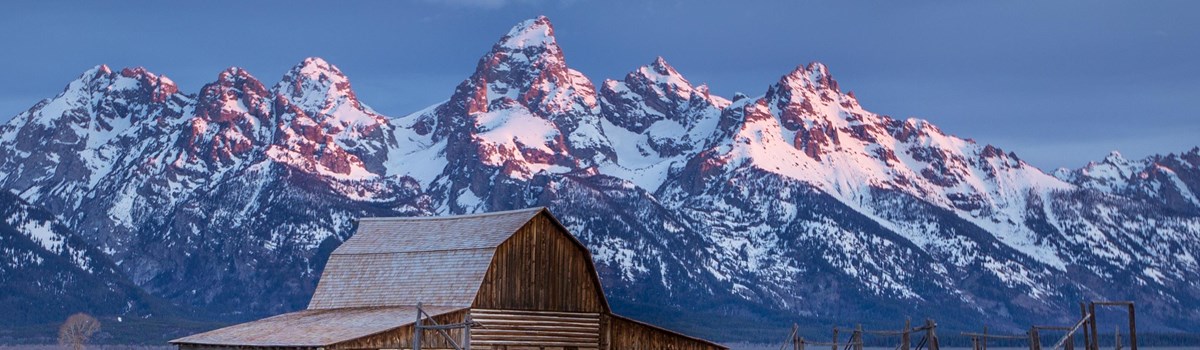 A barn with mountains behind.