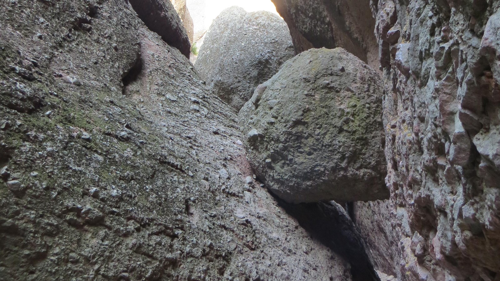 Narrow rock passage in Balconies Cave with daylight visible through an opening above.
