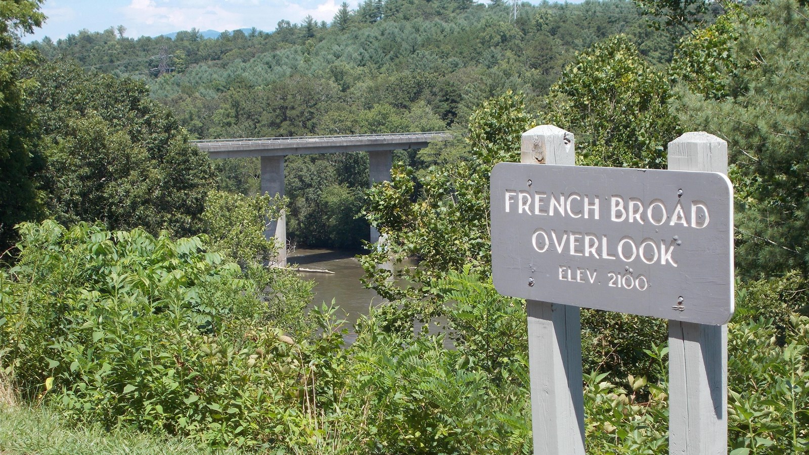 French Broad Overlook sign with river and bridge in the background