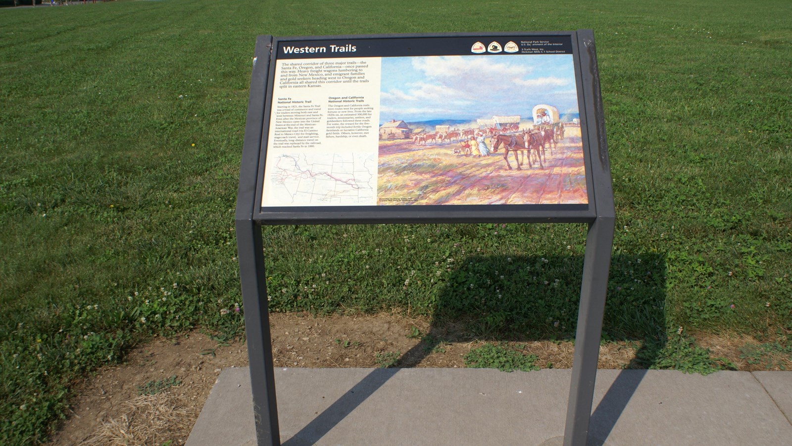 Interpretive panel featuring a colorful painting of a wagon train in a grassy field