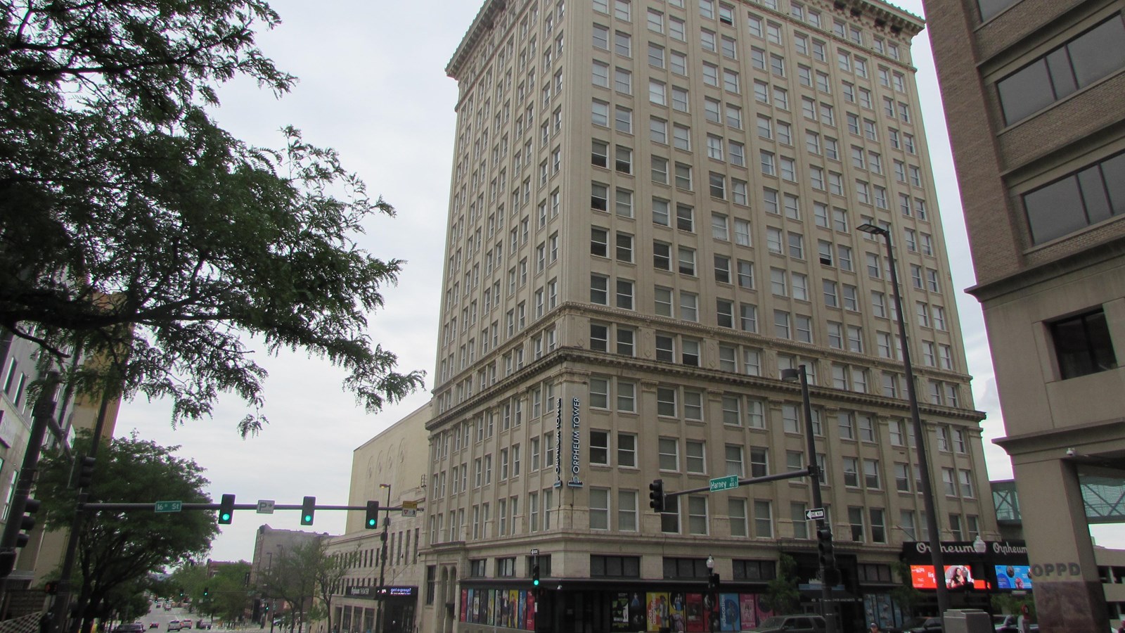 Sixteen story bank building at downtown corner. Theater building attached to side, mid-block.