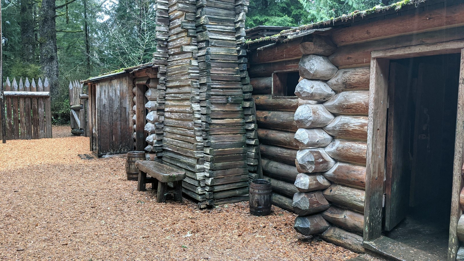 A row of rooms made of stacked logs and a large wooden chimney
