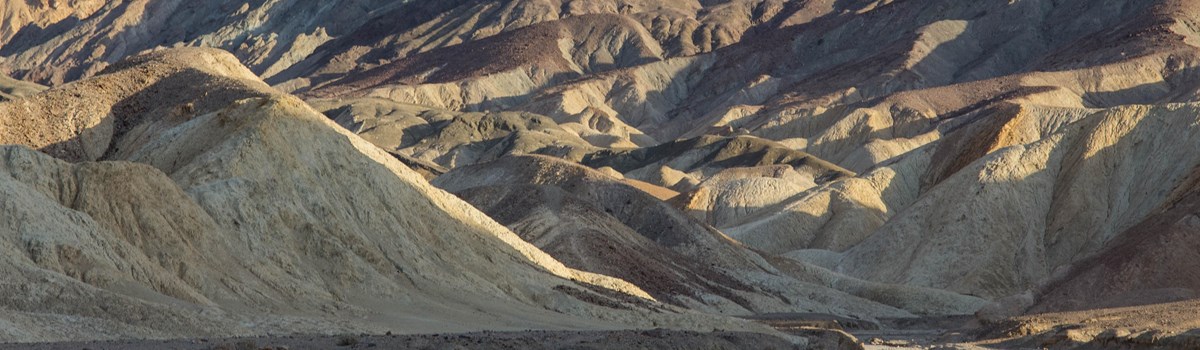 Highly eroded, multi-hued hills, contrasted in afternoon light.