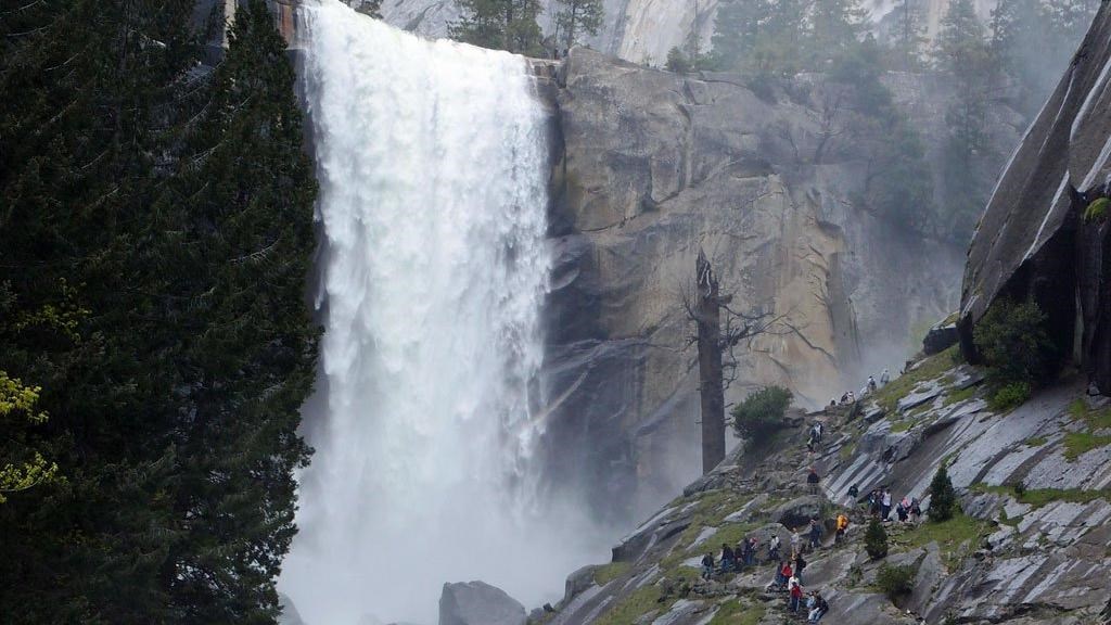 A full Vernal Fall with hikers along the rock steps of the Mist Trail