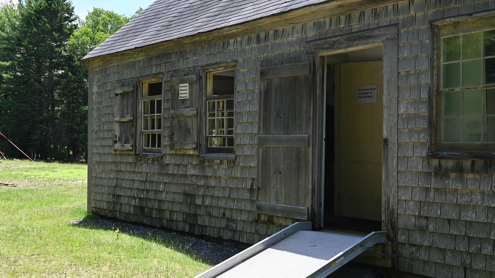 Old Wooden building with a metal ramp leading into the open doorway.