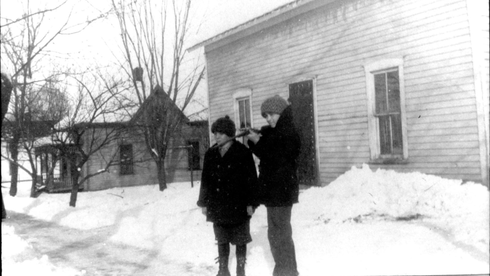 A 1910 photo shows two boys in the snow on a small town street.