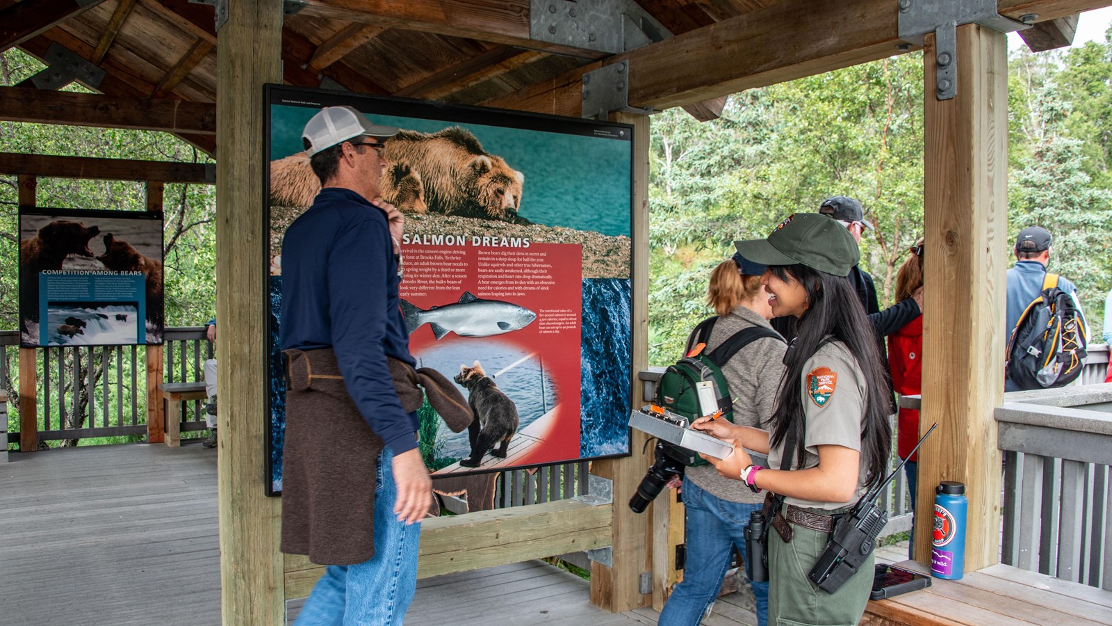 A ranger holds a clip board while visitors walk past