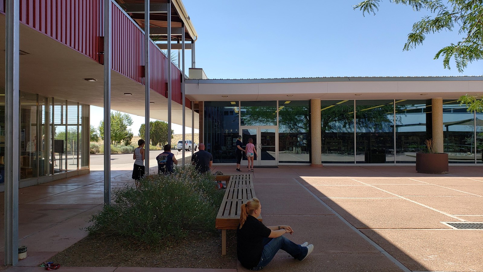 Mid-Century style architecture around people in a shady plaza.