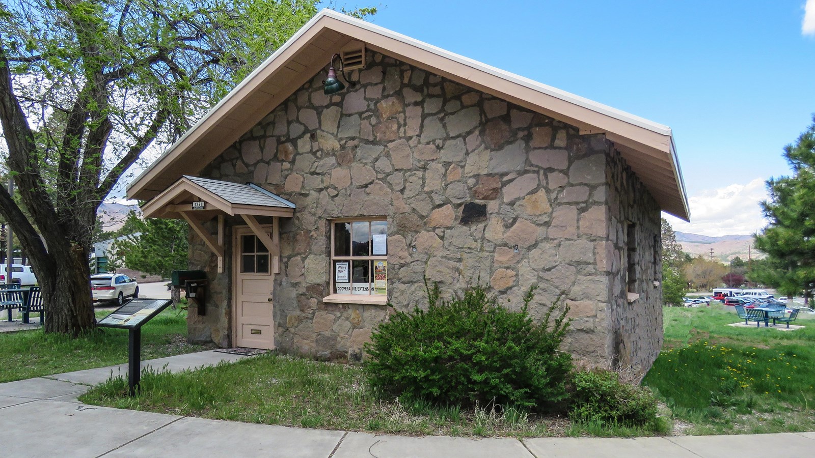 A small stone house sits set back from the sidewalk.