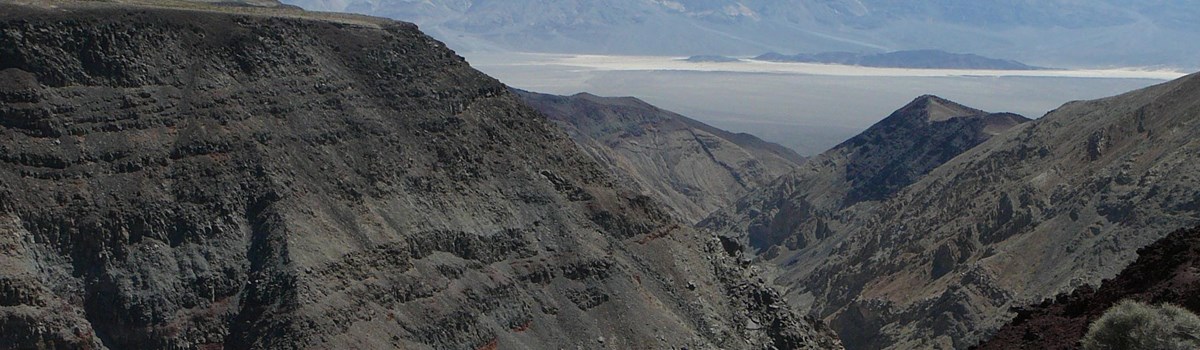 Looking down a colorful canyon with distant desert mountains.