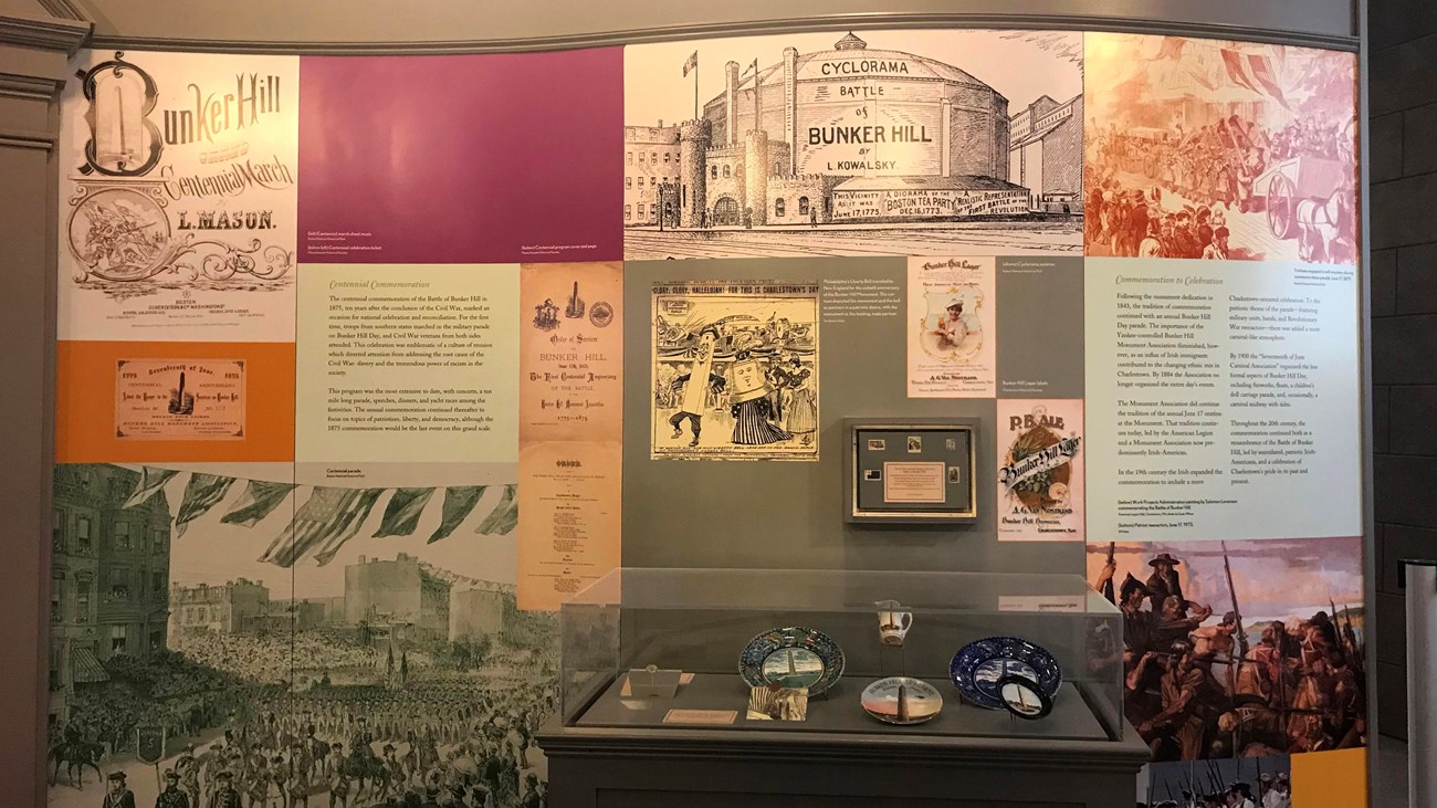 A wall of an exhibit filled with images and text. A glass case of artifacts sits in front. 