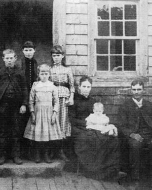 Historic photograph of a family standing in front of a farmhouse