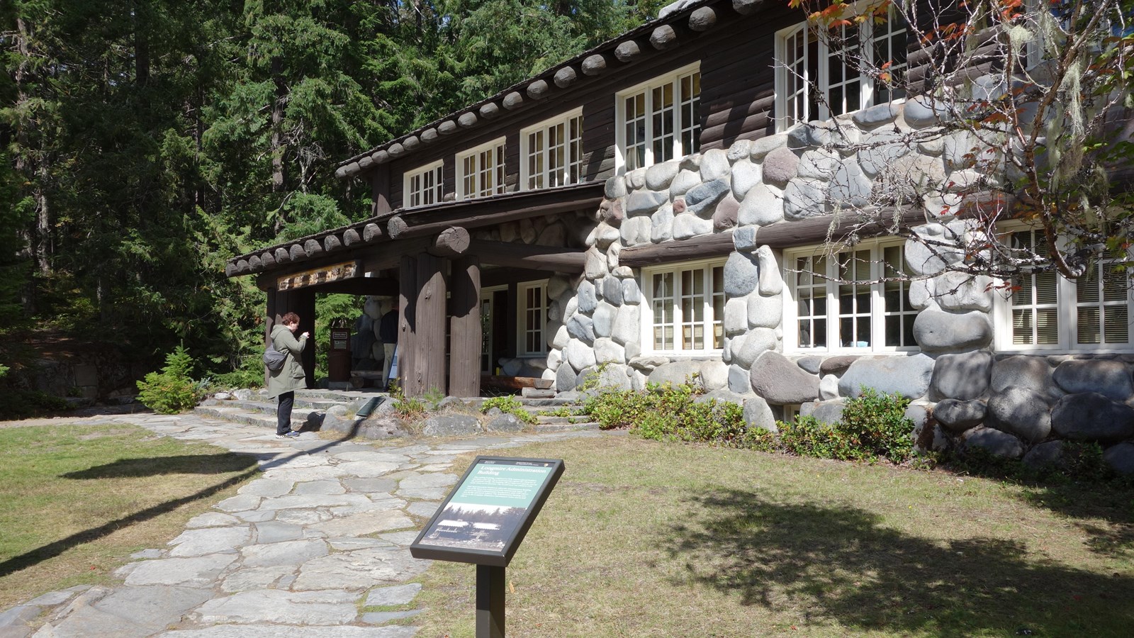 A small wayside next to a stone path leading to a wood and stone two-story building.
