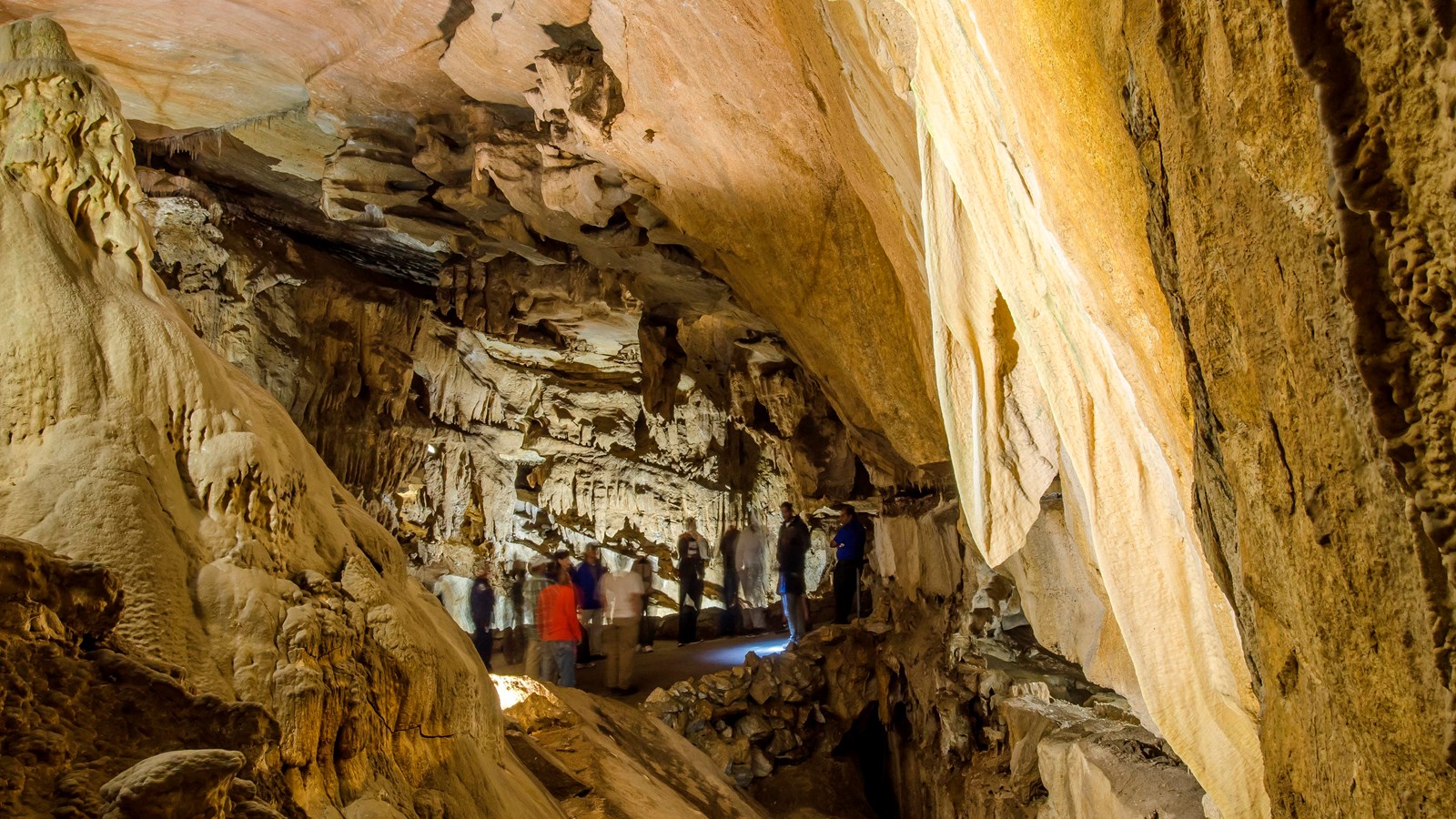 A large room made of marble walls with a group of 9 people in the distance 