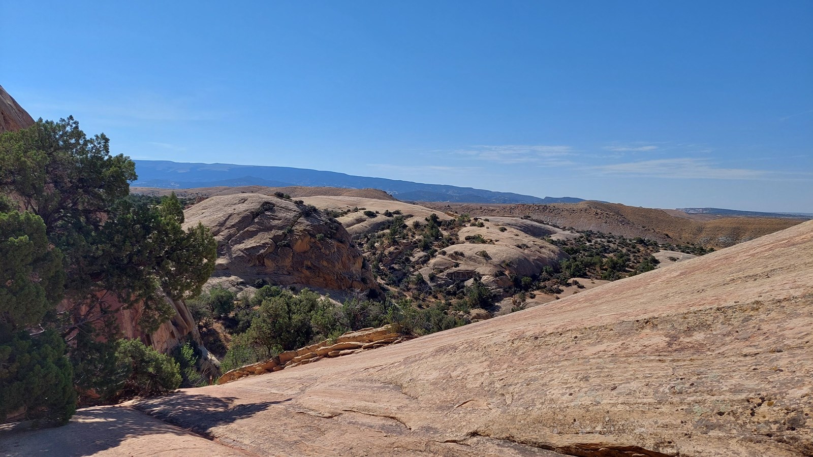 Smooth sandstone bluffs and cliffs rolling across red rock desert landscape.