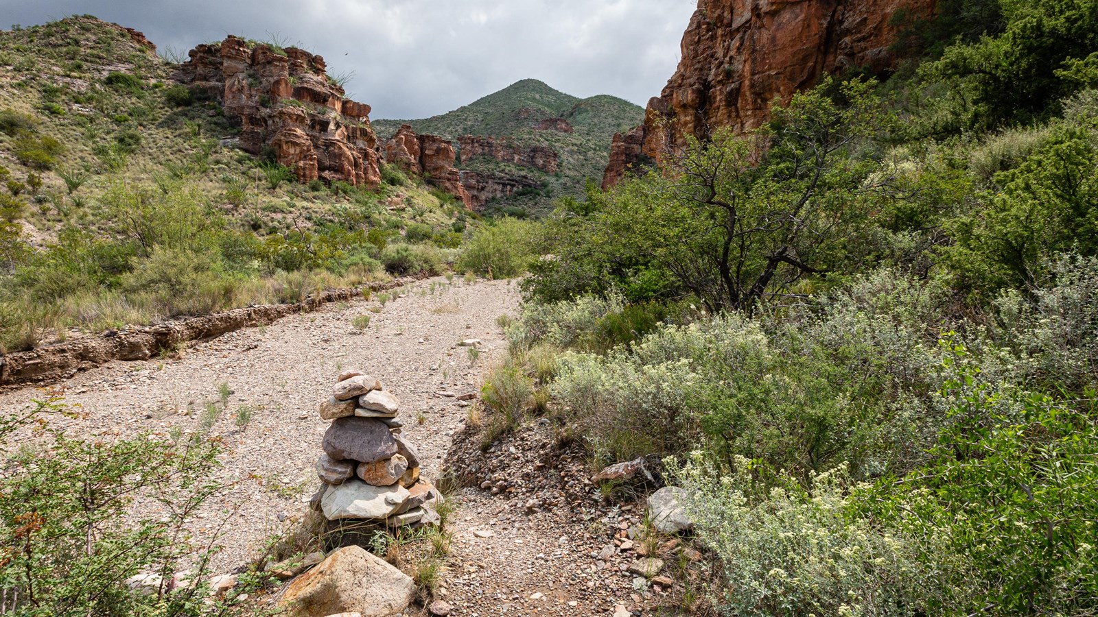 A rock cairn marks route into a sandy wash.