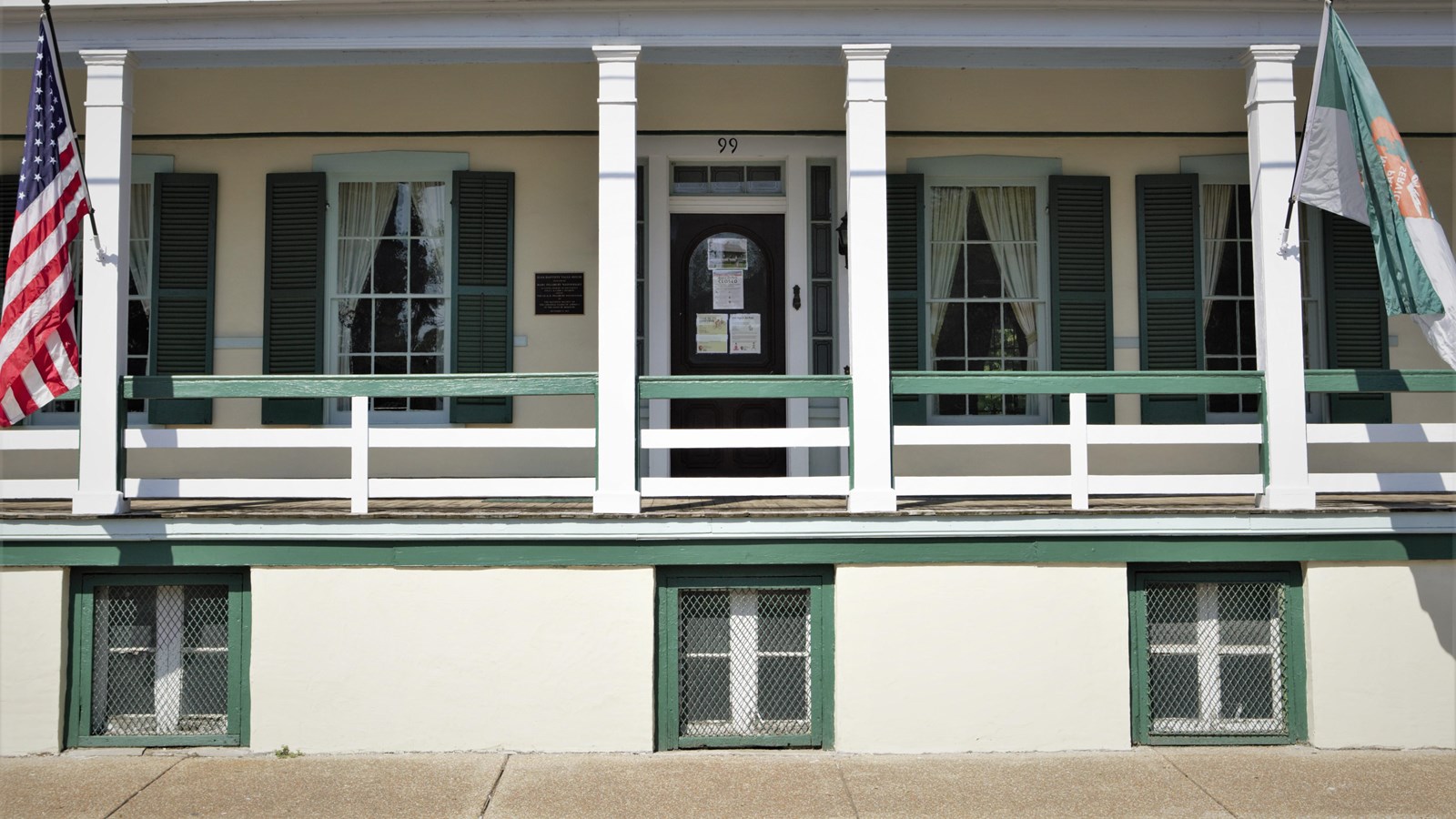 Green and white building. American flag and NPS green and grey flag sit on posts.