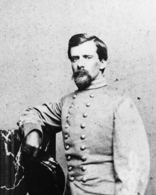 An 1800s full portrait photograph shows a young bearded man in an army uniform.