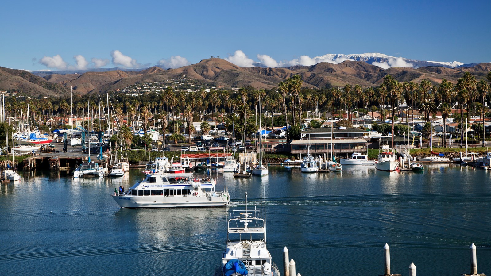 boat in harbor with mountains behind covered in snow. 