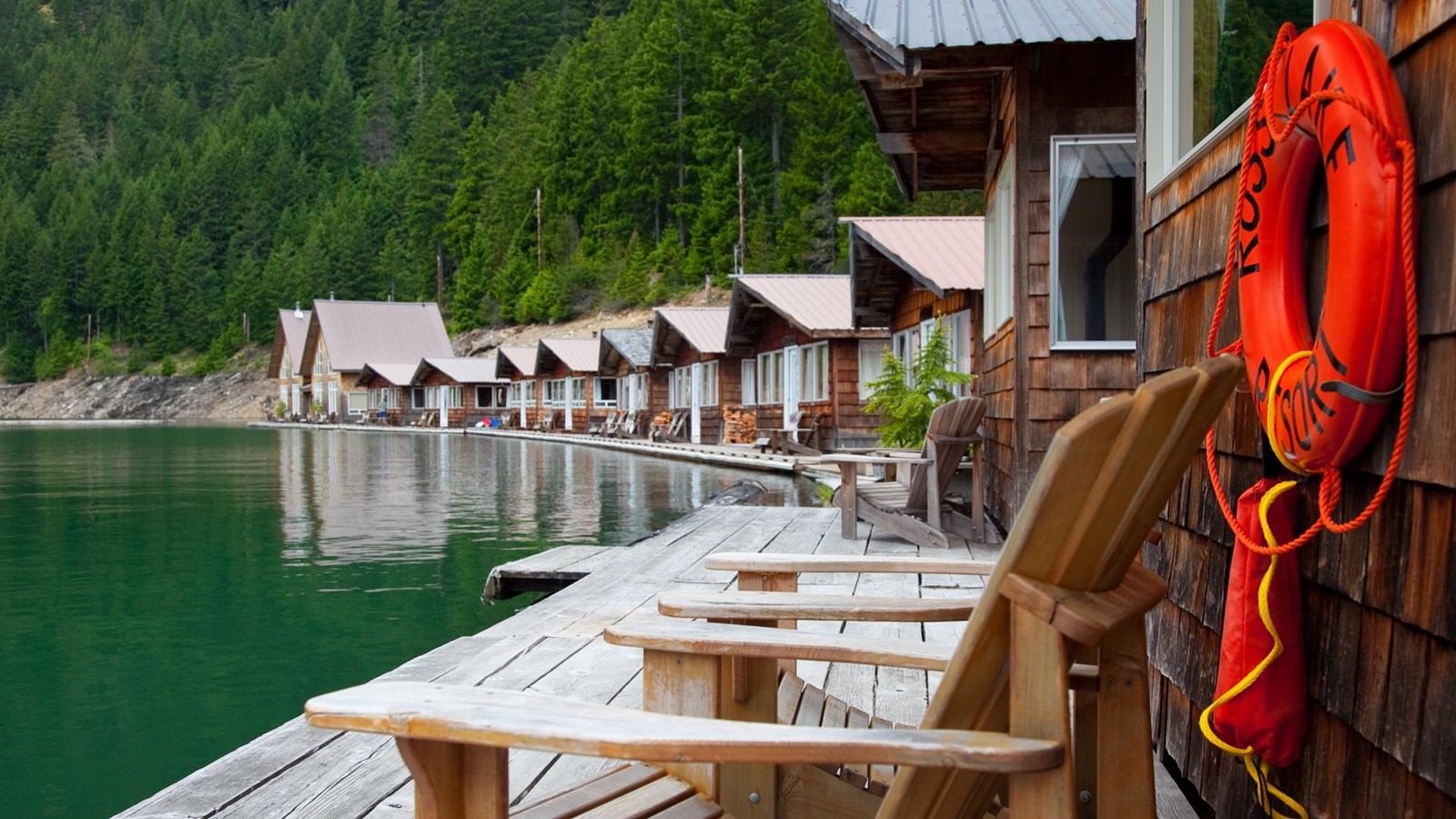 A row of cabins along a green lakeshore.