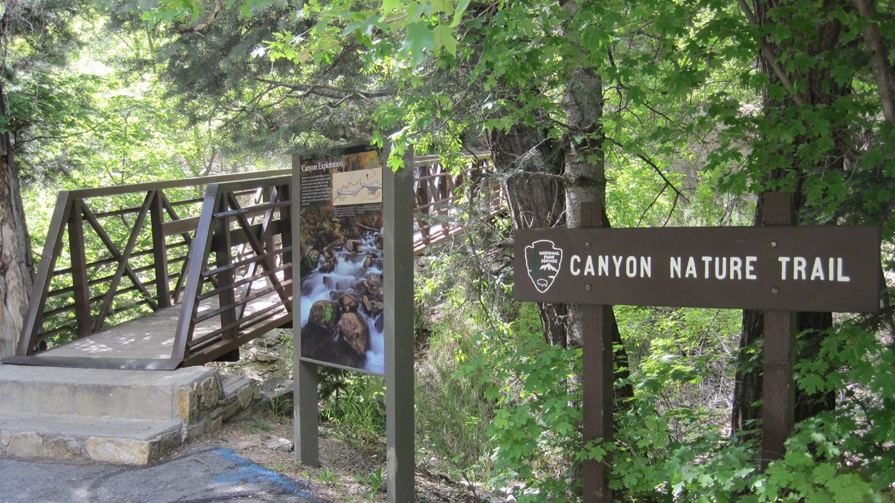 Two steps leading up to a bridge next to a sign reading 