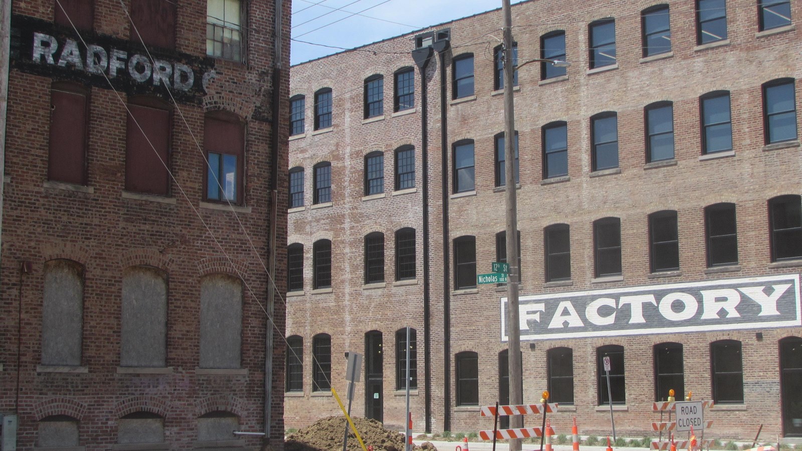 Brick warehouse buildings undergoing rehabilitation separated by a street 