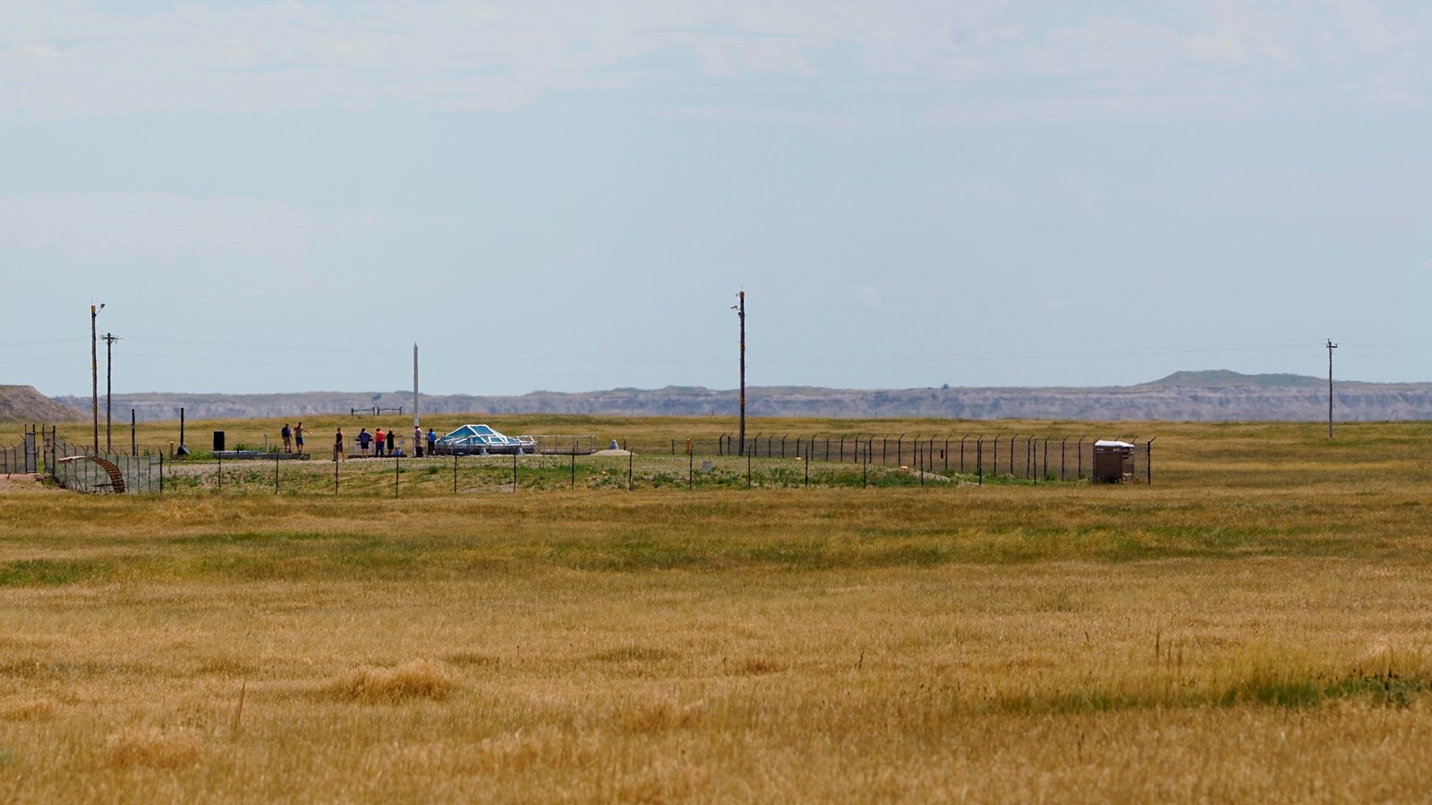 A fenced compound in the foreground is surrounded by prairie landscape 