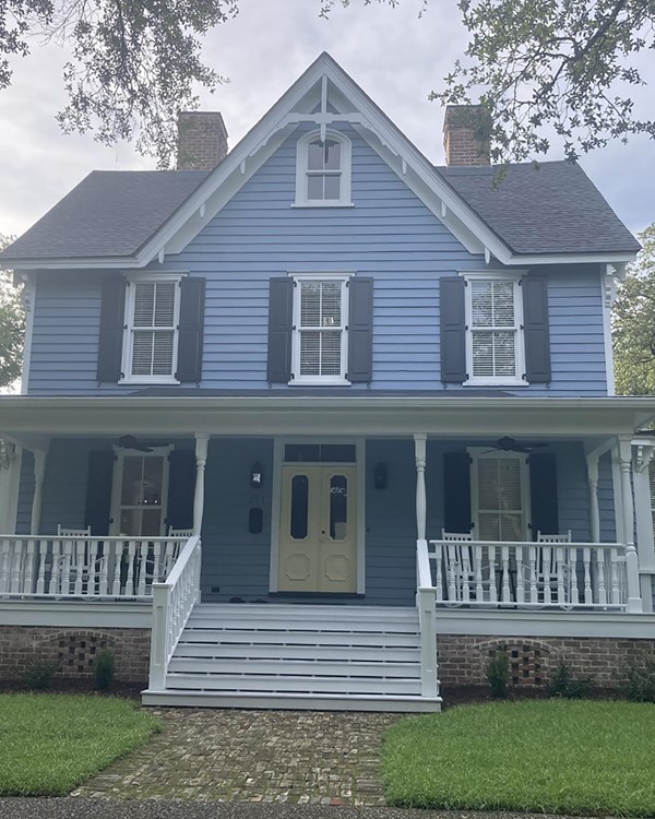 2 story wooden home, painted blue with a wrap around porch