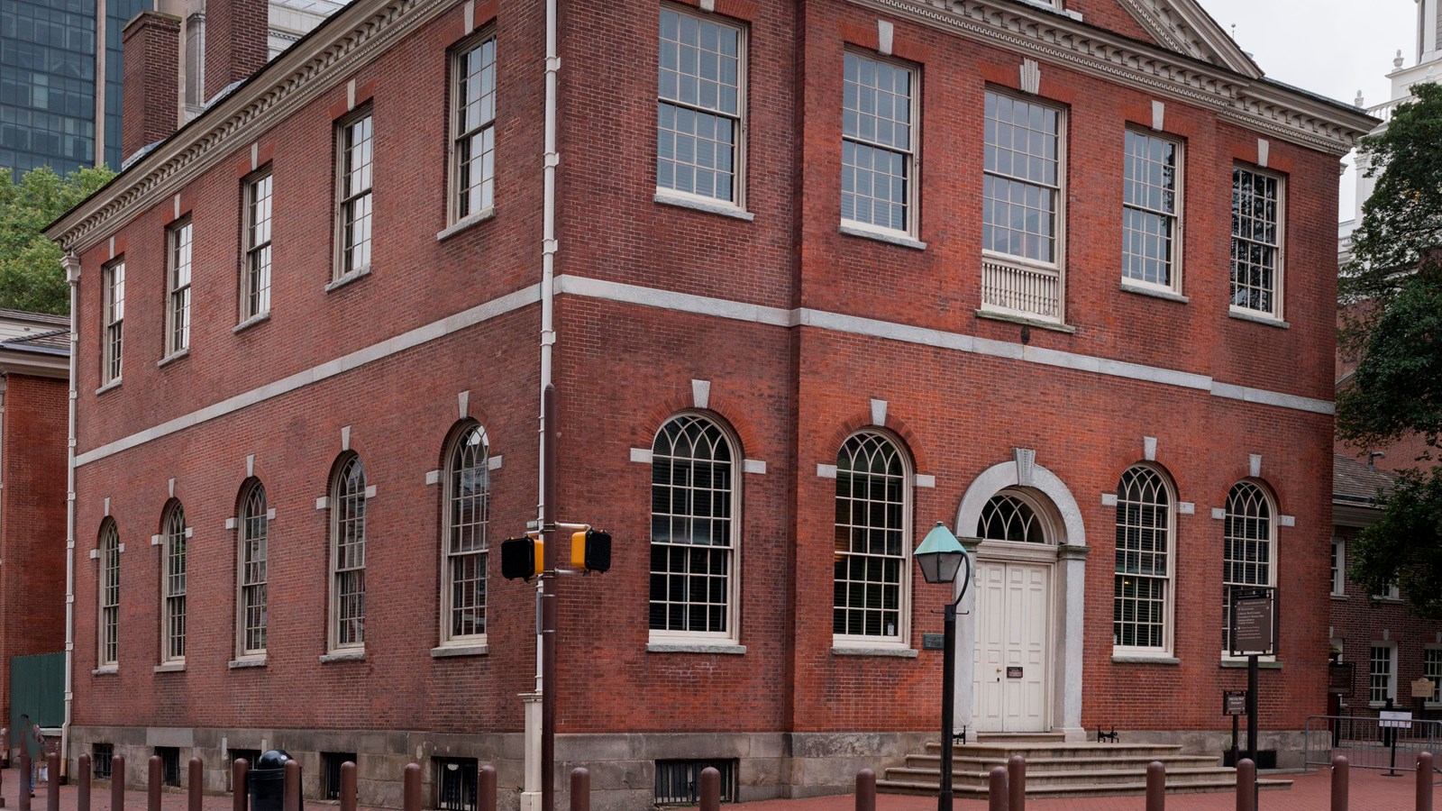 A color photo of the exterior of a two story red brick building with a triangular pediment