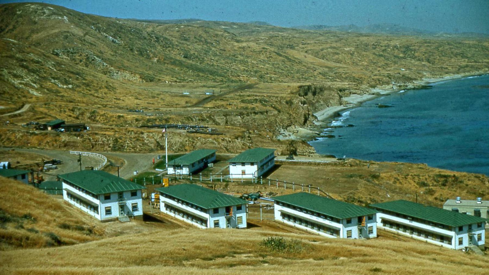 Military baracks on hillside overlooking ocean.