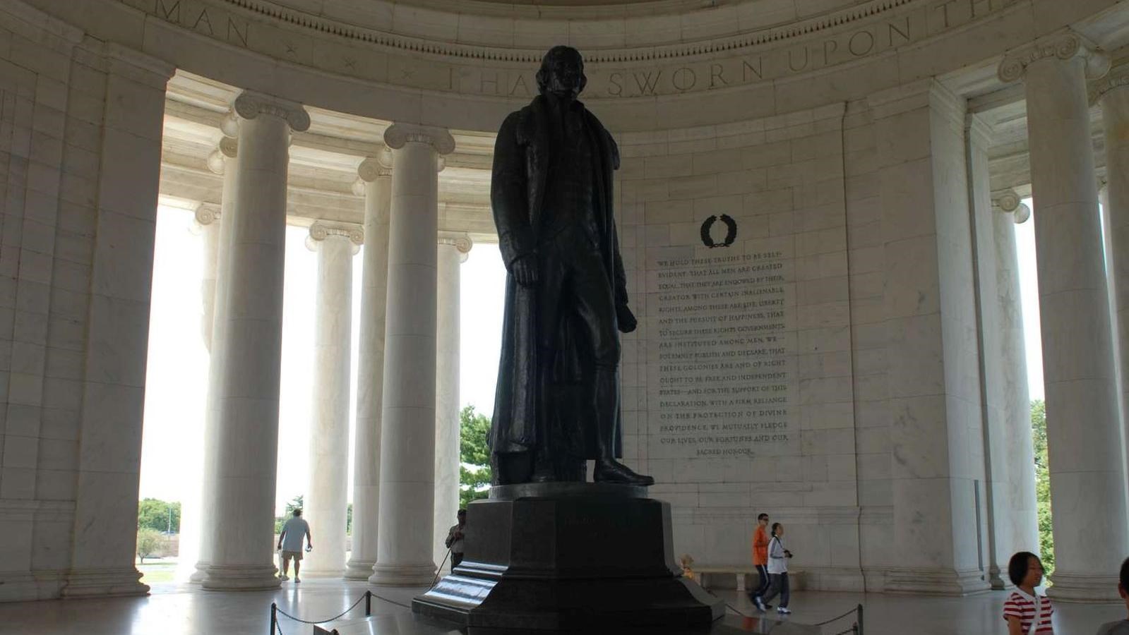 Larger-than-life statue in round memorial with inscriptions and columns.