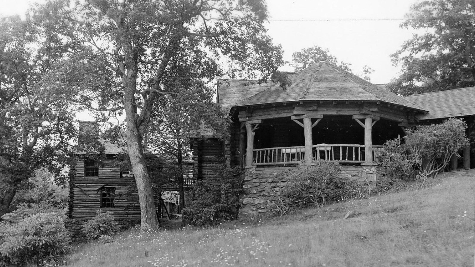 Historic black and white photo of wooden and stone dining room and kitchen buildings