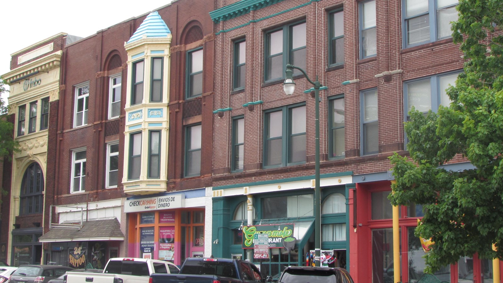 Series of three-story brick commercial buildings, painted cornices and storefronts.
