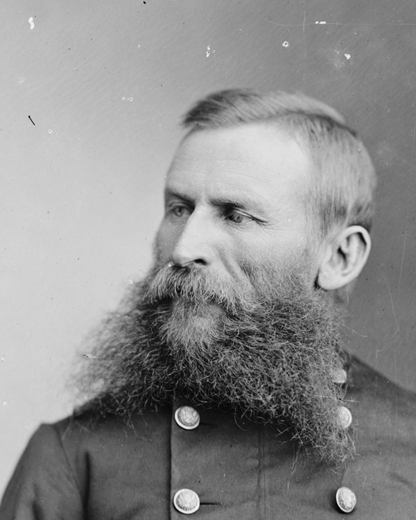 An 1870s half-portrait photo shows a fork-bearded man seated in double-breasted army uniform.
