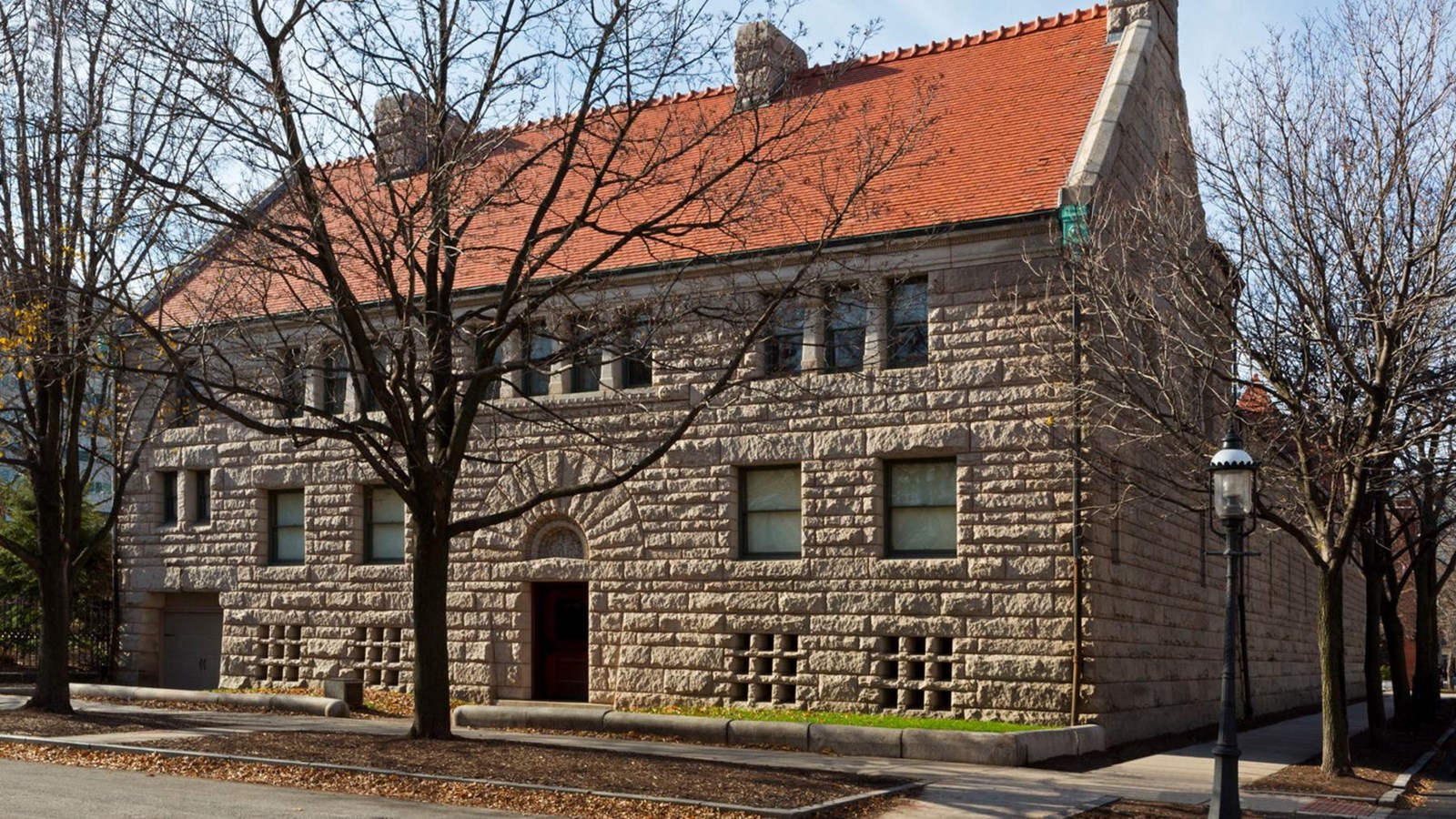 A brownstone three story home with a copper colored roof. 