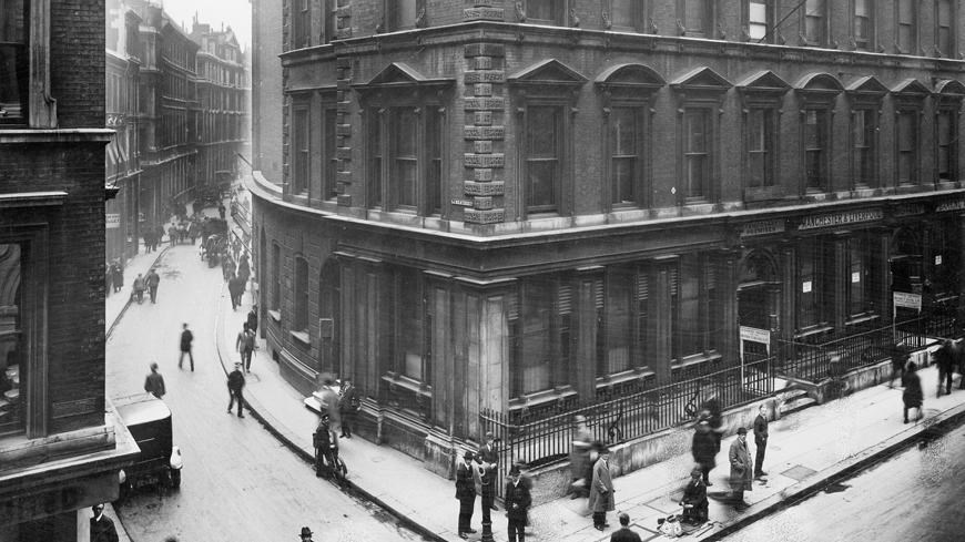 Black and white photograph of a Victorian building on a busy street