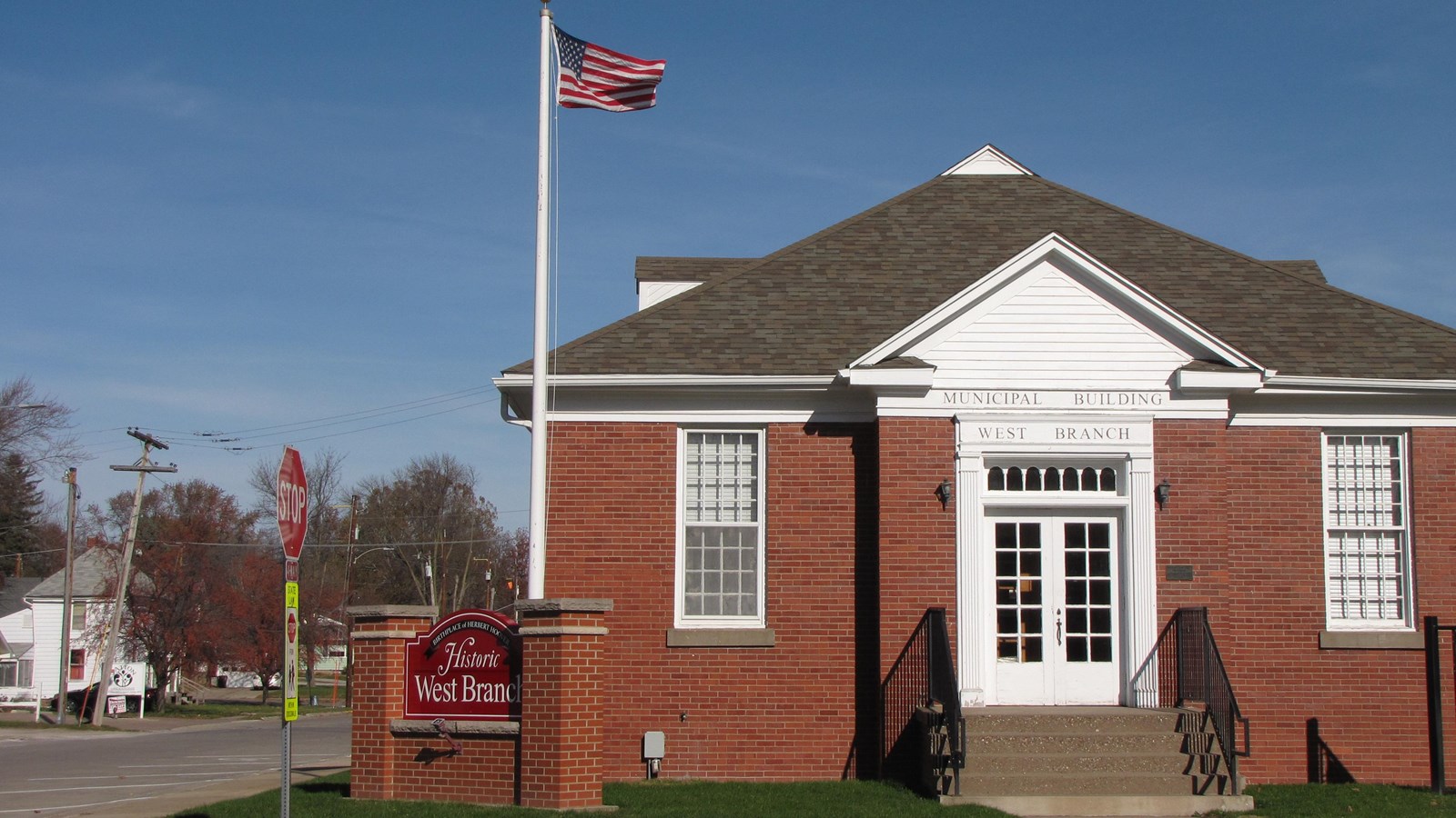 A U.S. flag flies at red brick municipal building with a white portico.