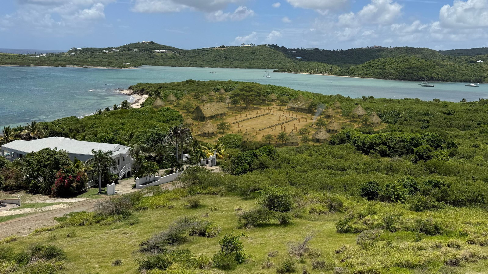 Taíno village overlay on modern St. Croix shoreline landscape with batey and thatched homes.