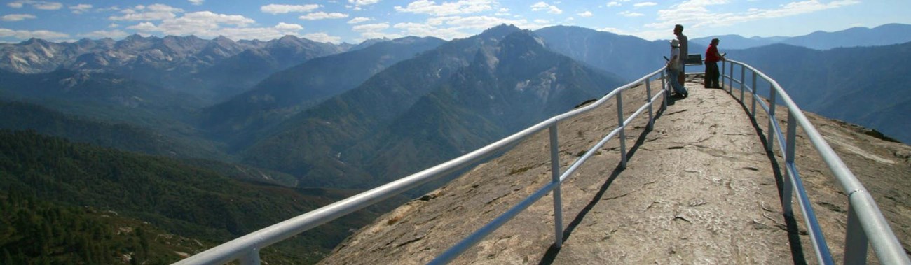 People stand along the narrow ridge of Moro Rock, surrounded by railing. Photo Paul Johnson