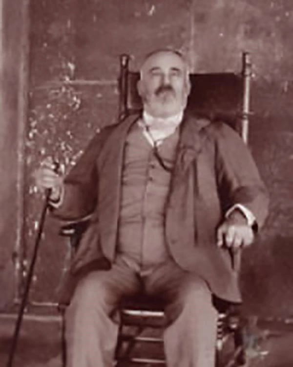 Middle-aged man sitting in a wooden chair wearing a suit