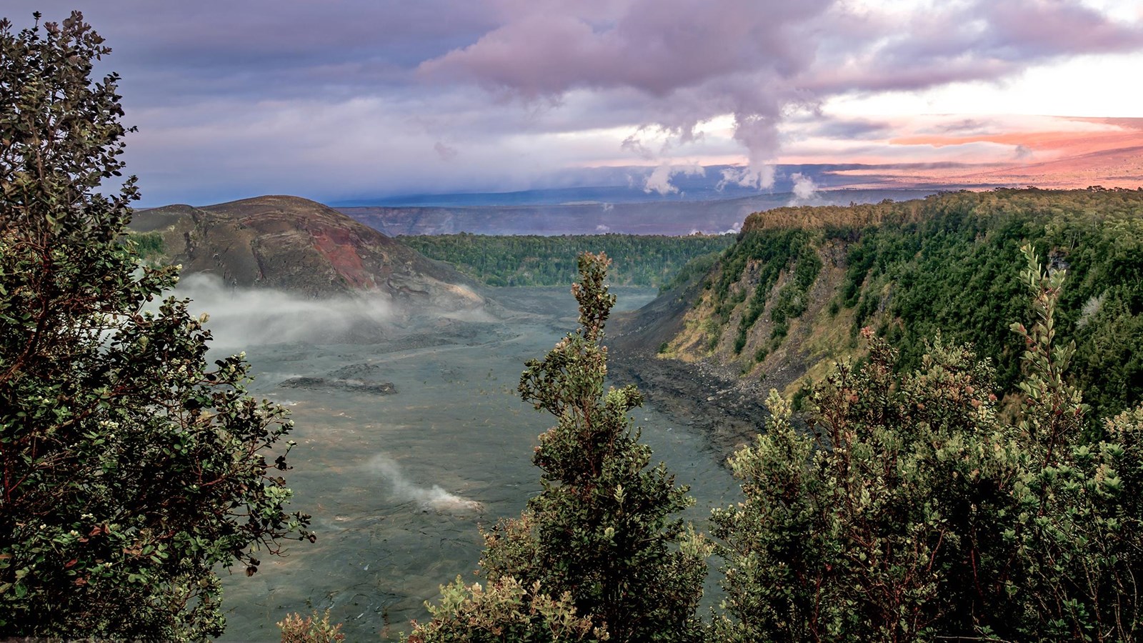 A volcanic crater at sunrise with trees in the foreground
