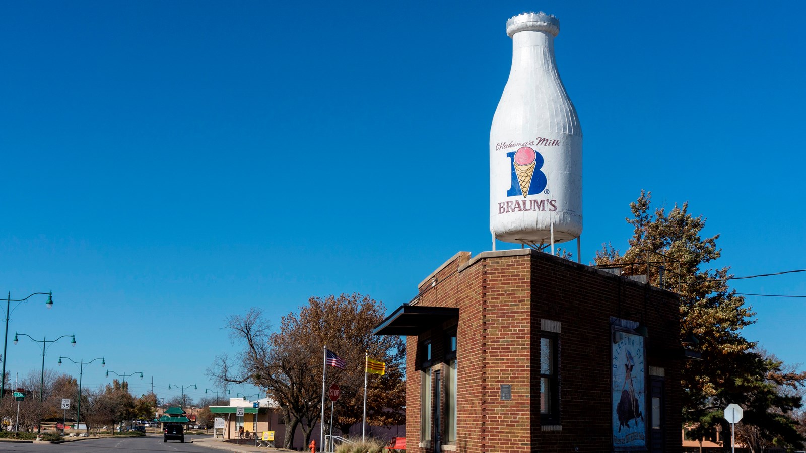 A small triangular brick building with a large milk-bottle sculpture on the roof.