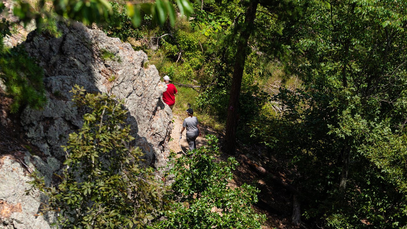 Two people hike along a rocky trail.