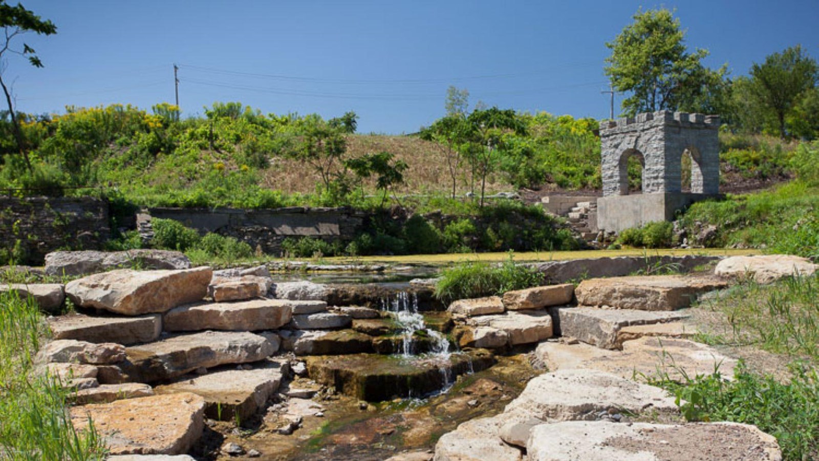 A pond forming in front of a cement structure. 