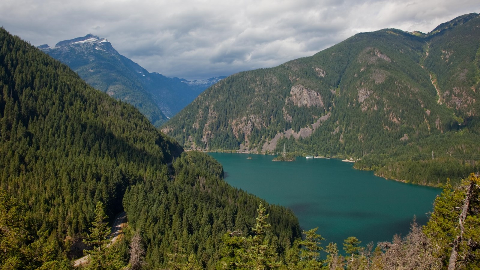 A blue lake surrounded by forested mountains.