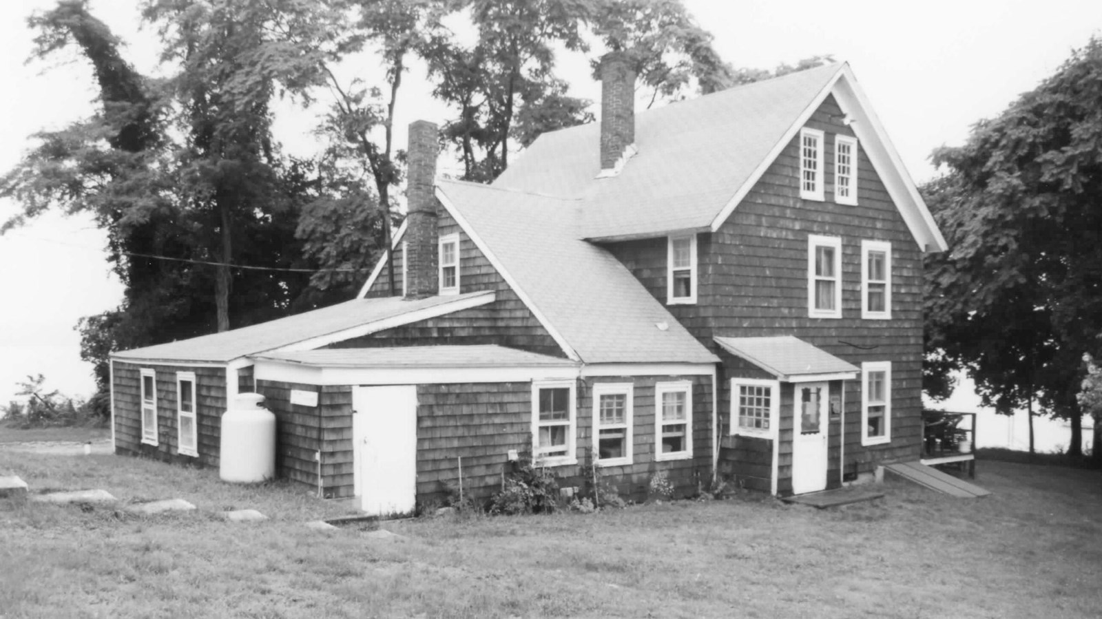 Three story building with shiplap exterior and white roof and windowsills