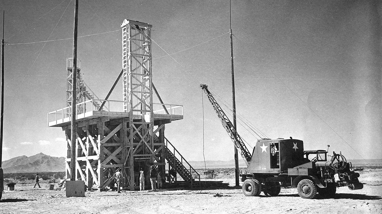 A black and white photo off a wooden tower and a crane.  