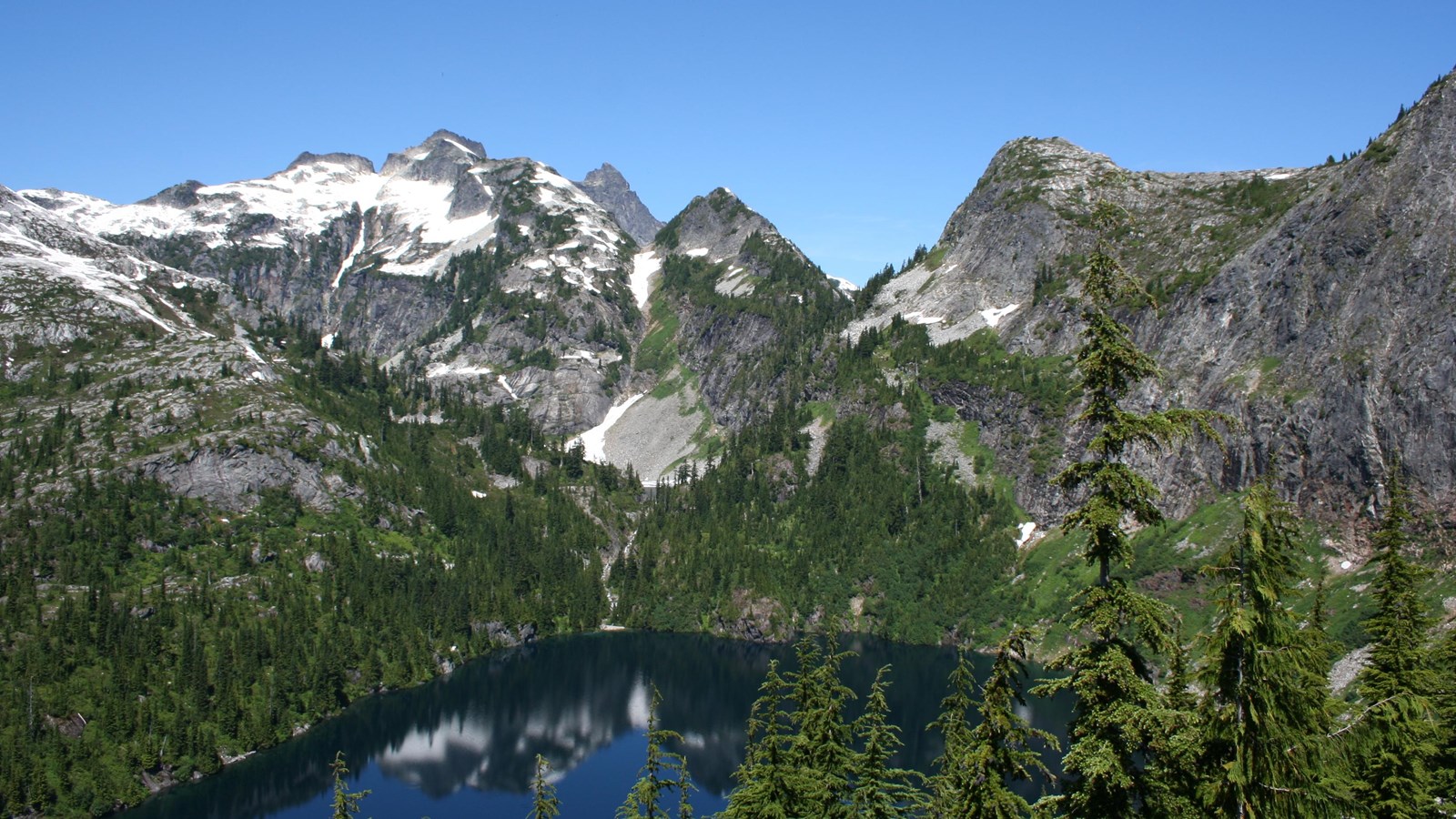 A blue lake surrounded by forested mountains.